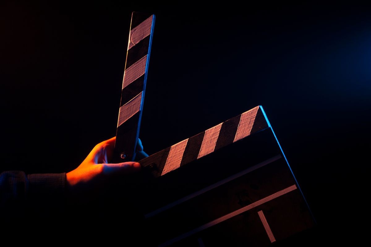 Opened clapperboard for cinema in hand, before filming on a black isolated background with red and blue backlighting