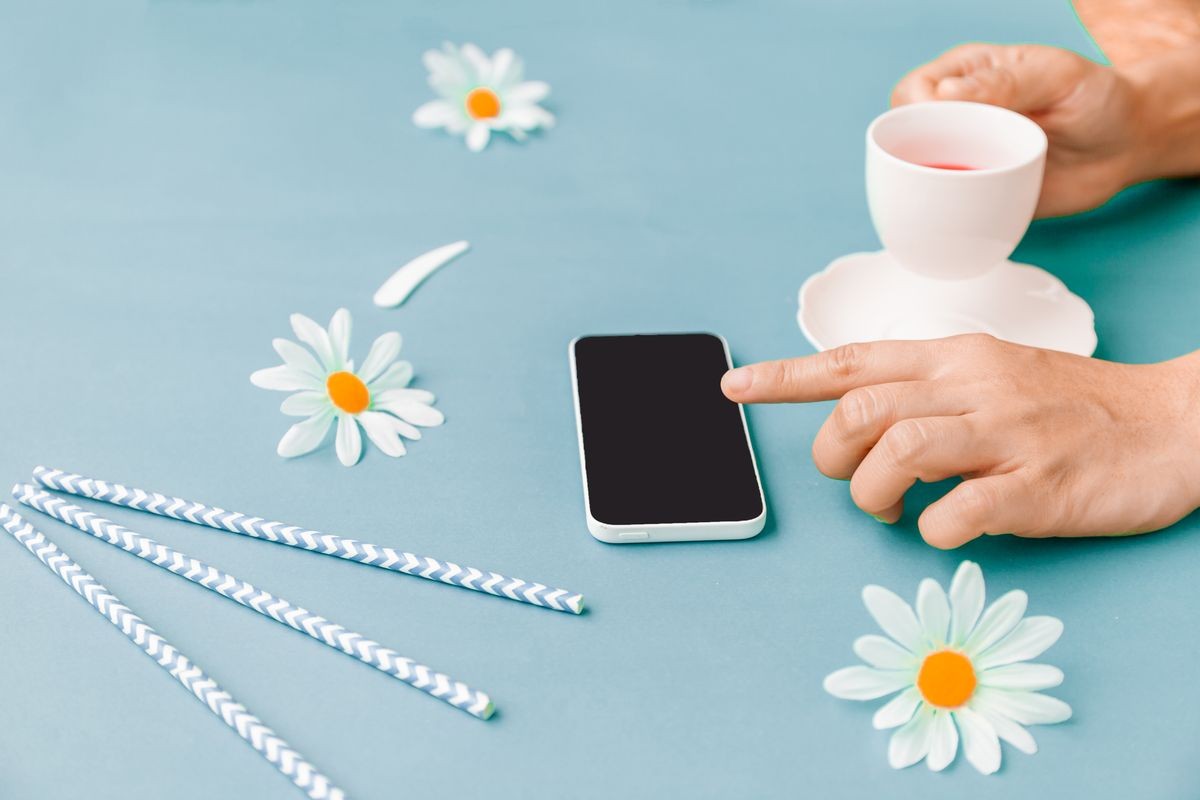 Using smart Phone with Cup of Tea Berry on pastel blue colors office table Mix for ladies and young girls .Post to Social Network and Social Media Online Internet On table desk in holidays.